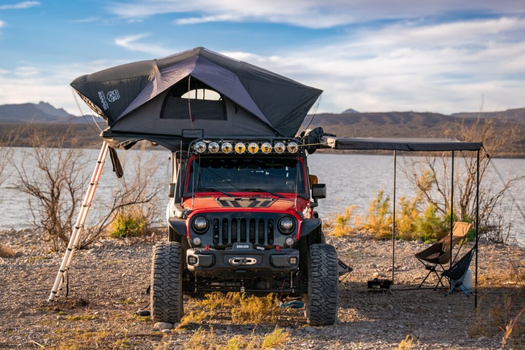 Clifford with its rooftop tent open at a lakeside camp