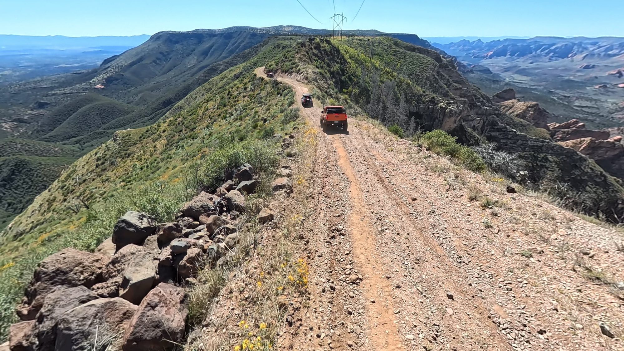 A red Jeep driving a narrow ridgeline road under power lines on Casner Mountain