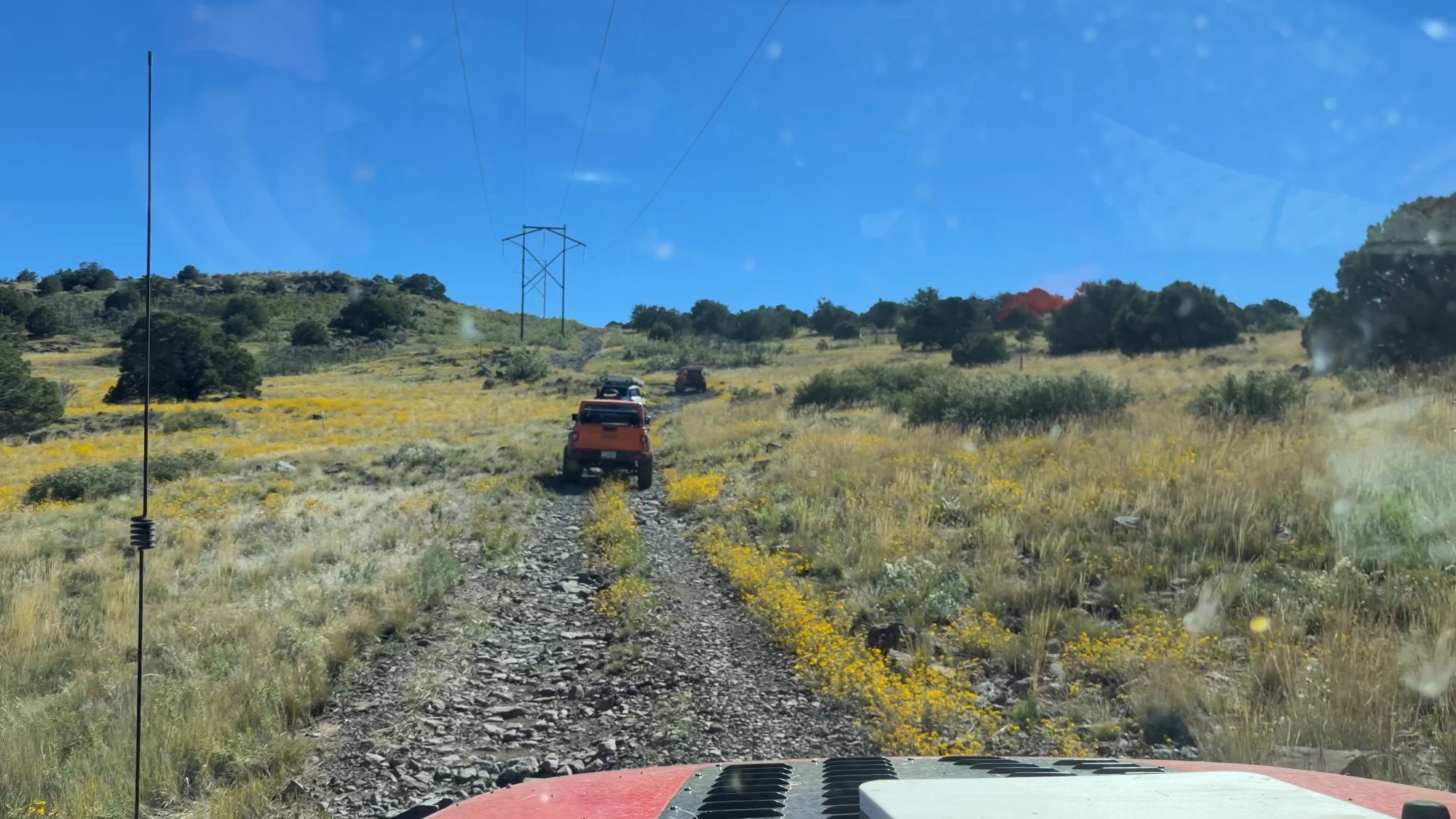 Jeep driving a two-track through a meadow under power lines