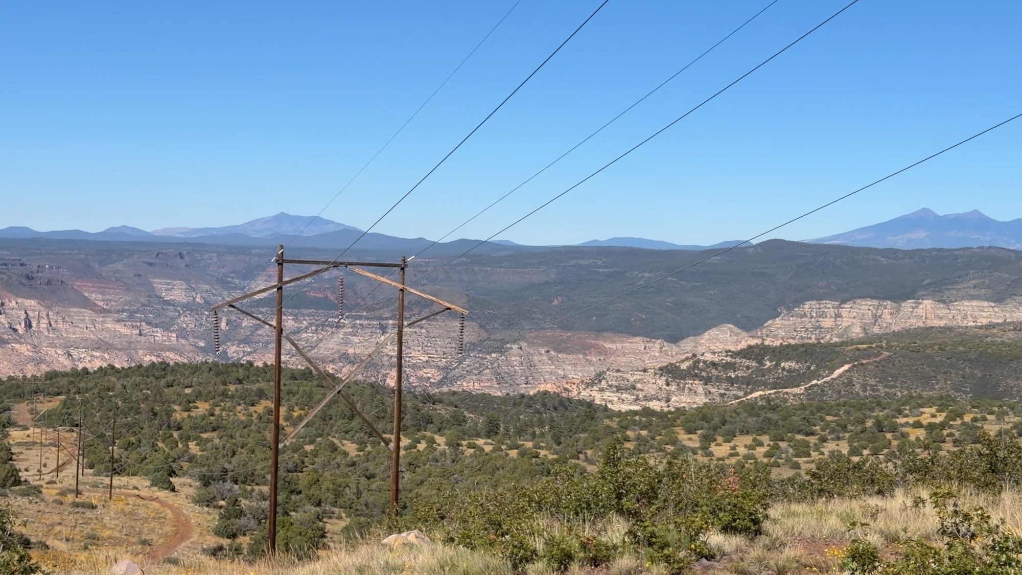 Power lines crossing a canyon with the San Francisco Peaks on the horizon