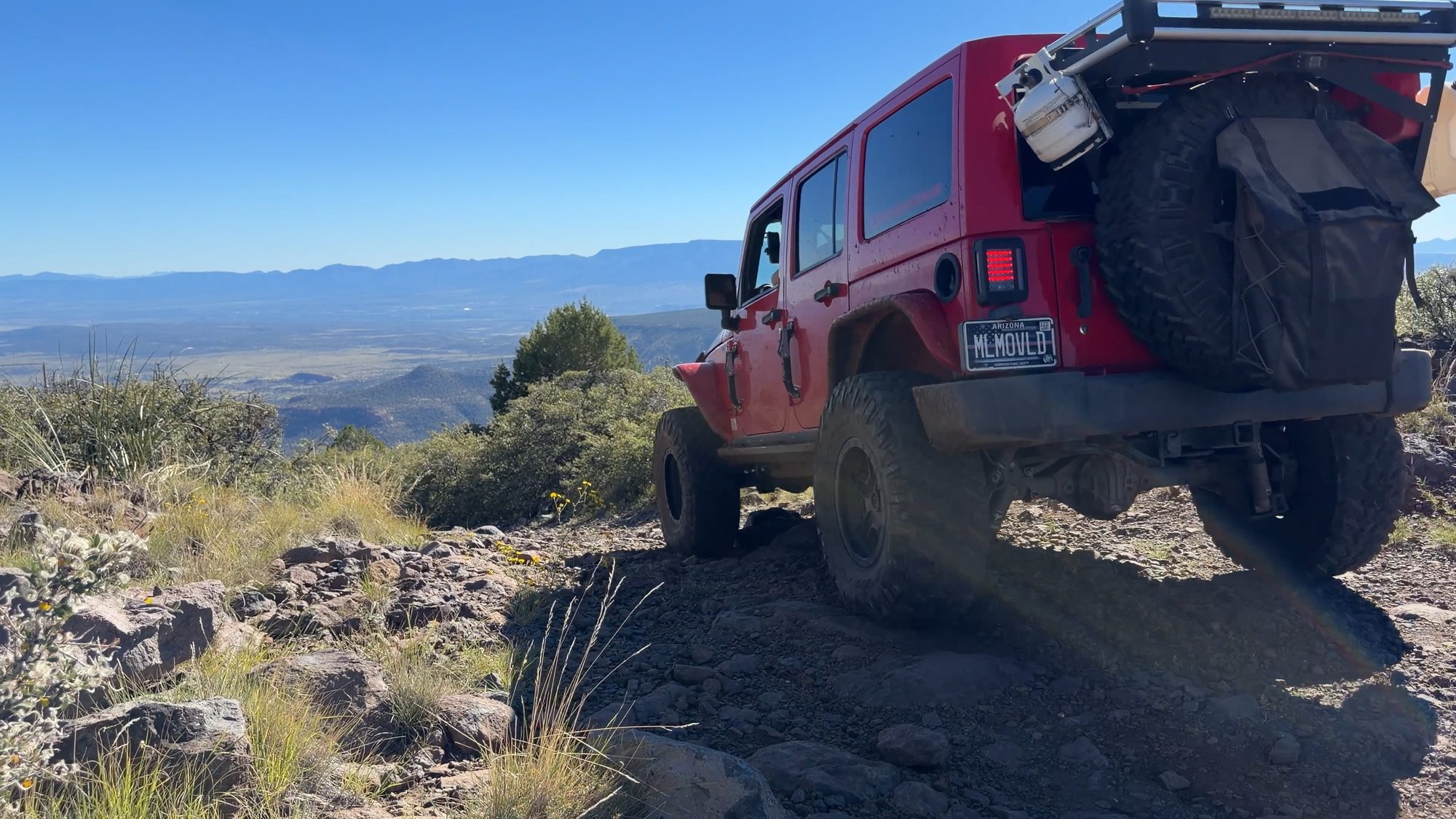 Red Jeep Wrangler on a rocky section above the valley