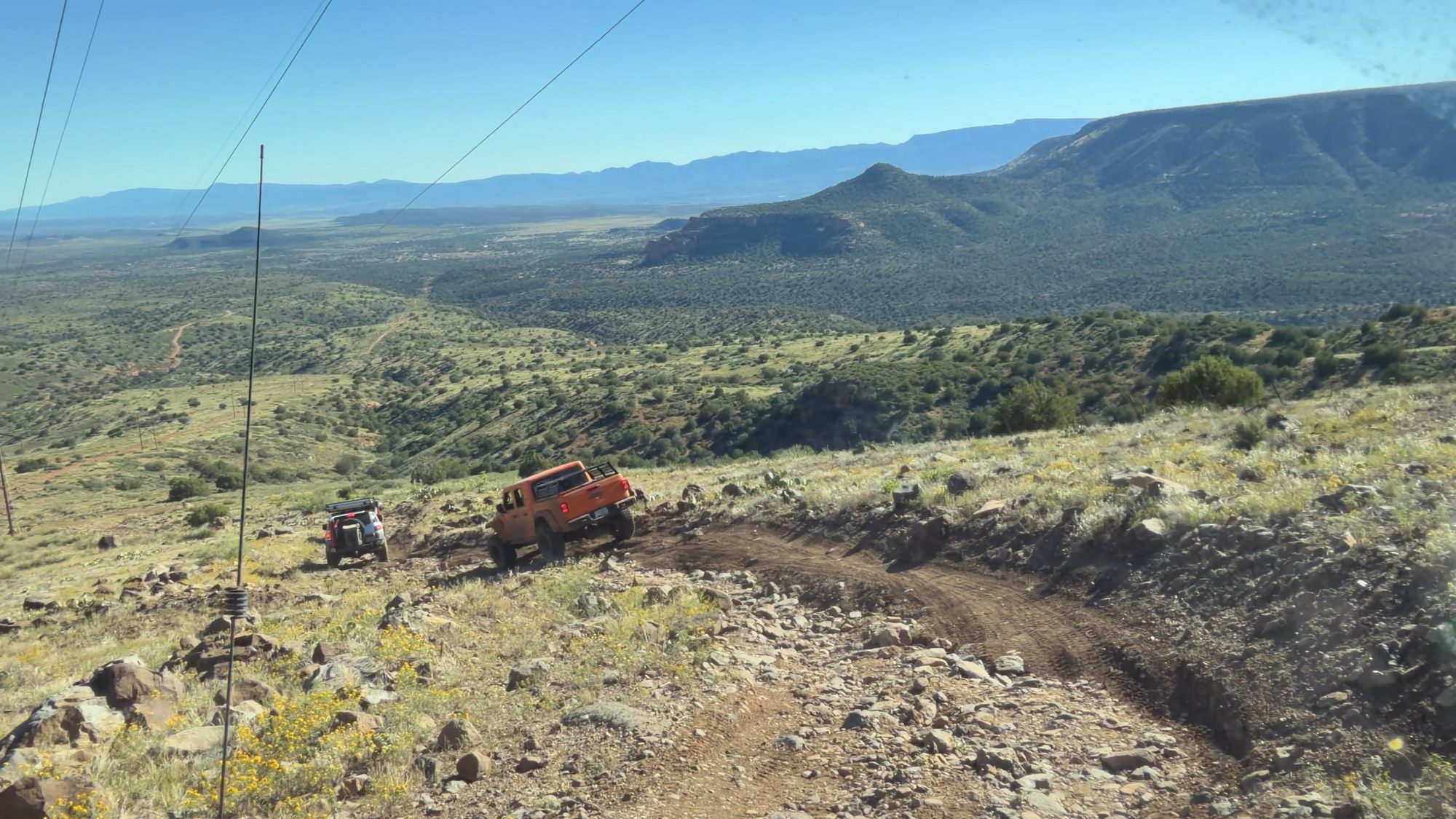Jeeps working down eroded switchbacks far below a ridge