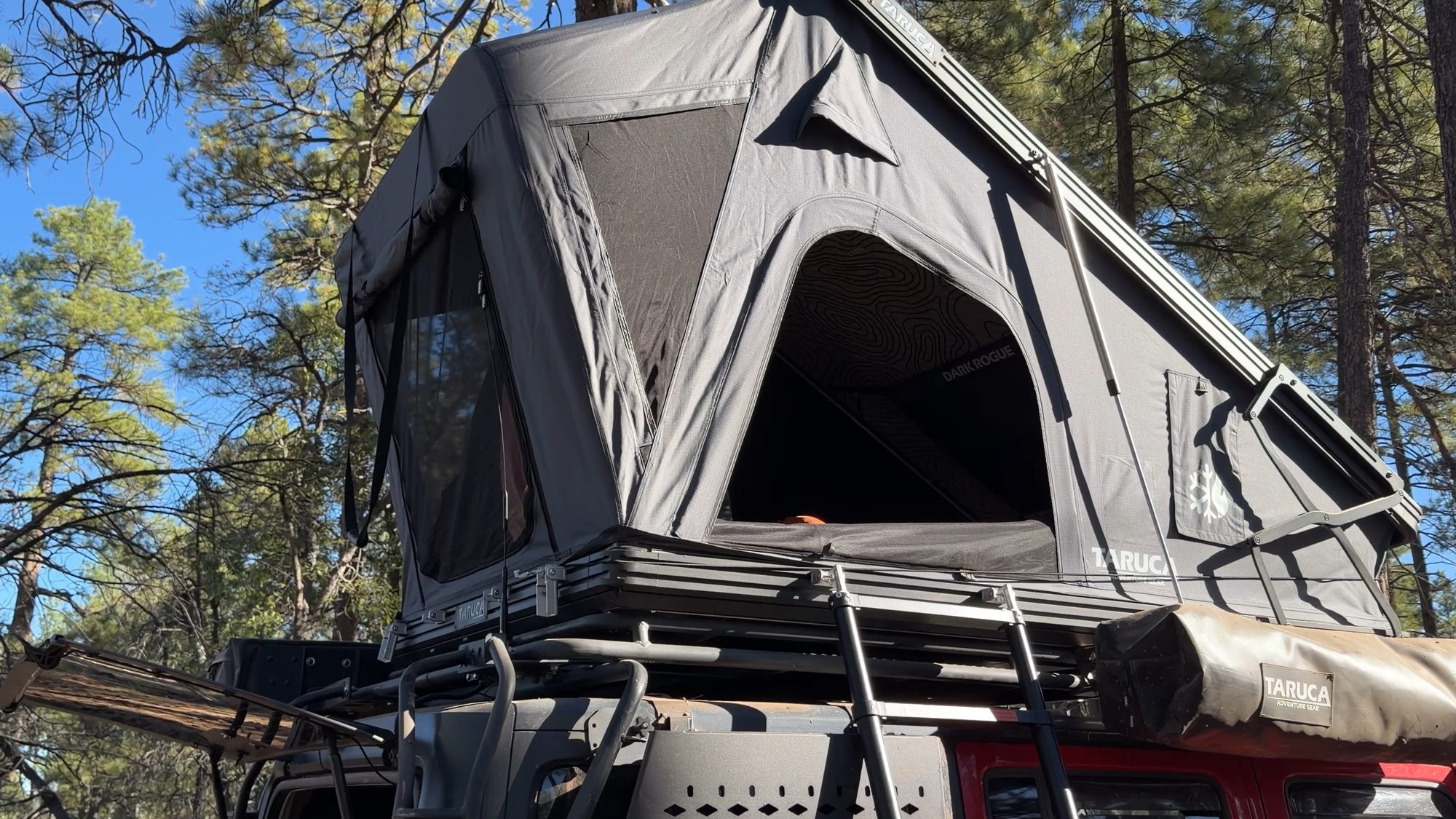 Taruca Dark Rogue 2.0 rooftop tent open on a Jeep in the pines