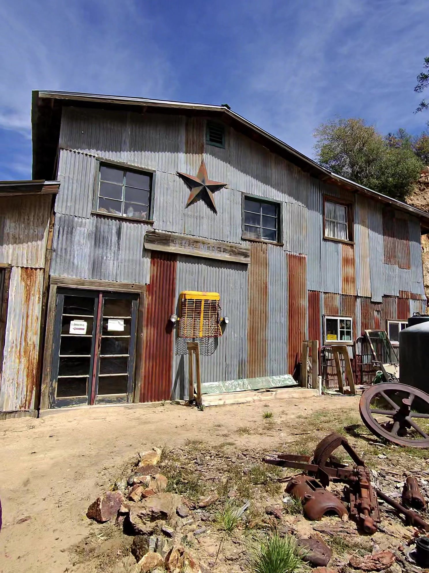 Corrugated metal exterior of The Mill restaurant in Crown King with a star on the gable and old mining equipment out front