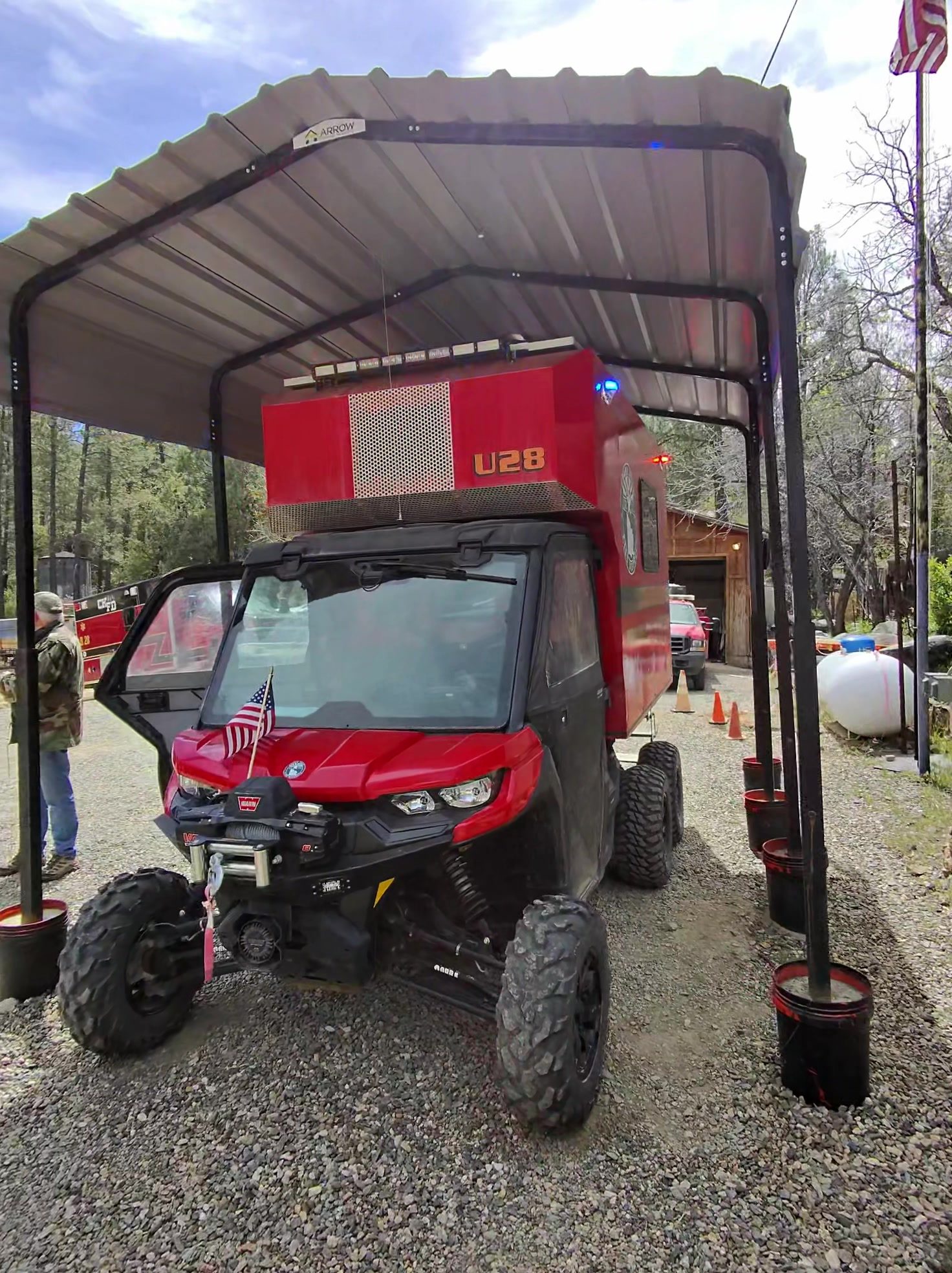 Red Crown King fire rescue side-by-side UTV with its lights on under a carport