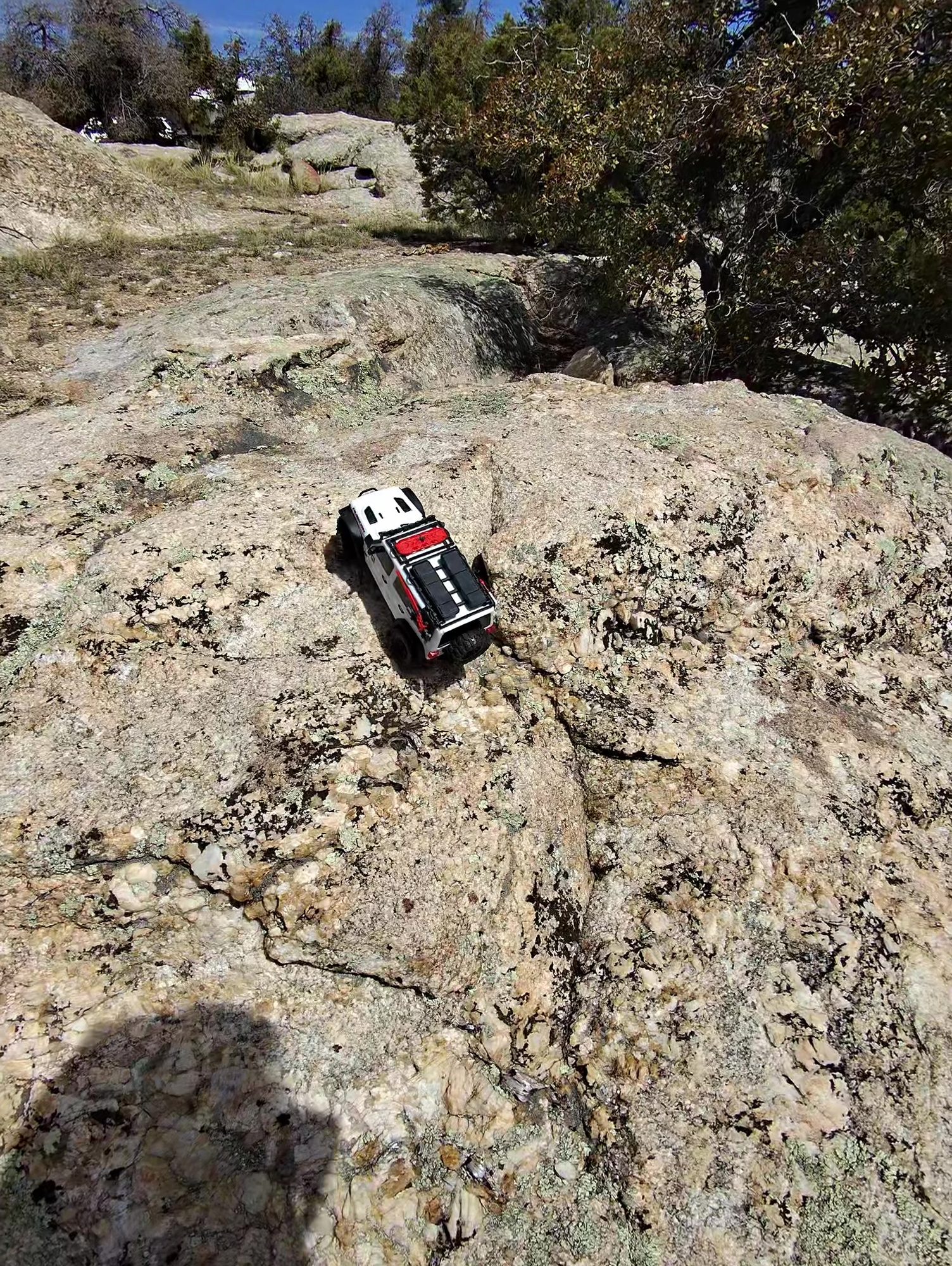 Small RC crawler climbing a large granite boulder