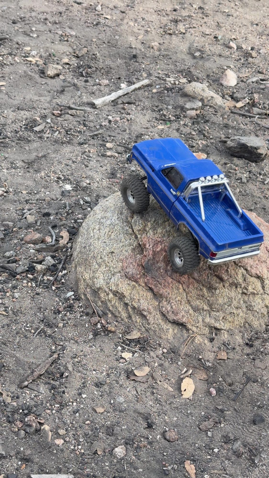 Blue scale RC pickup crawling over a boulder