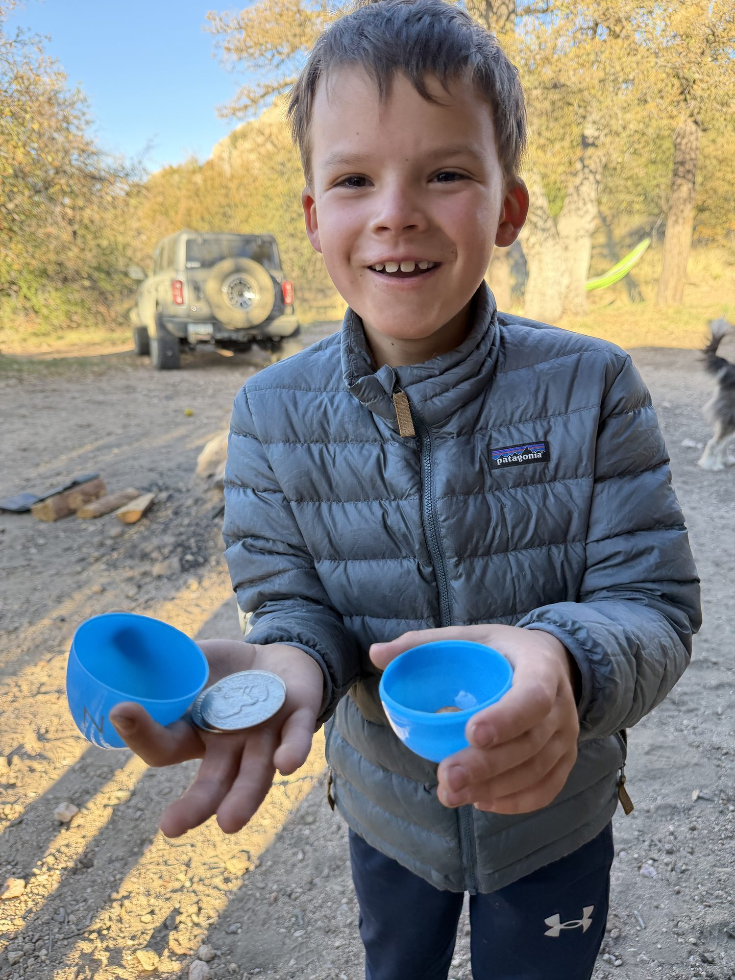 Smiling boy holding open blue plastic Easter eggs with coins inside