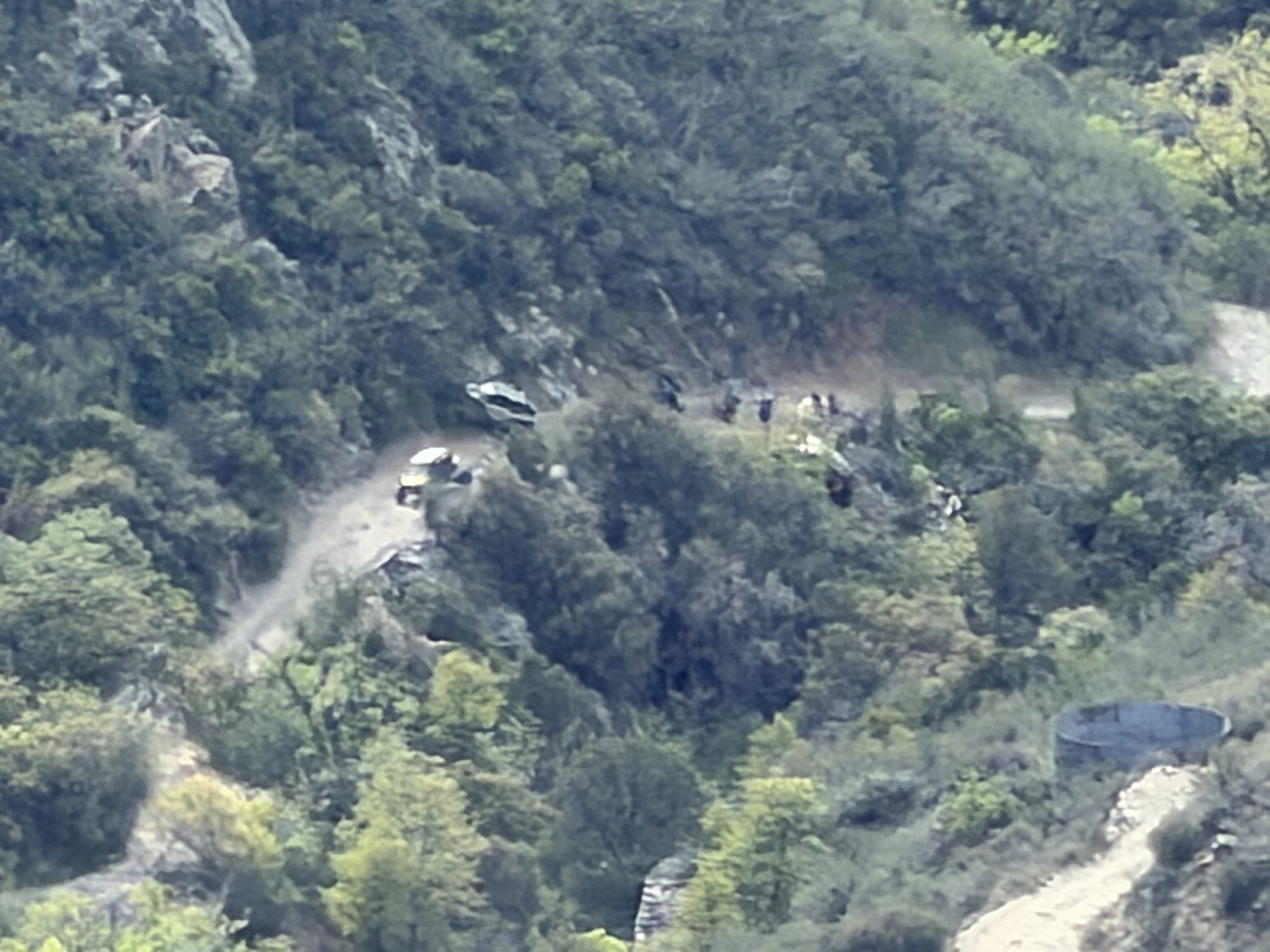 Zoomed view of vehicles stopped on a rocky trail on a canyon hillside during a recovery
