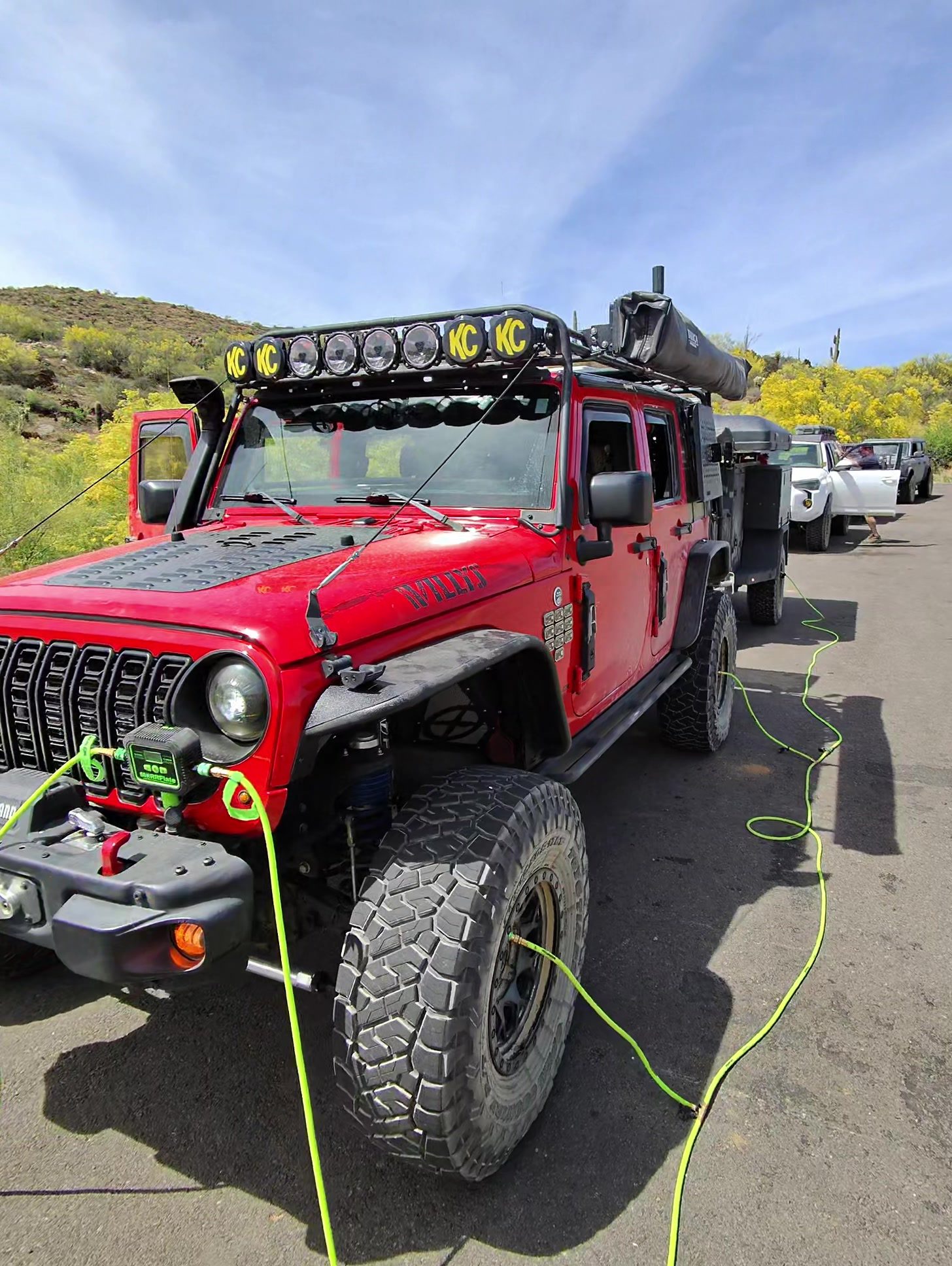 Red Jeep hooked up to MORRFlate hoses at a paved pullout while airing back up for the highway
