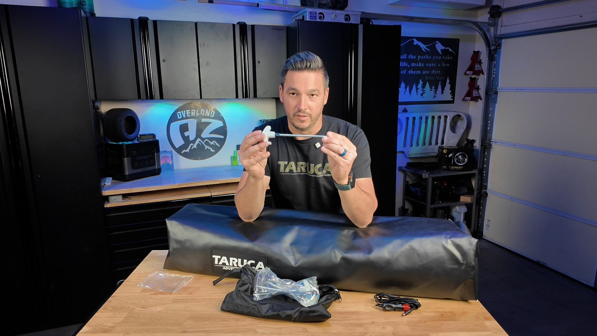 Josh holding a drill-in tent stake beside the packed Taruca ensuite and accessory bag
