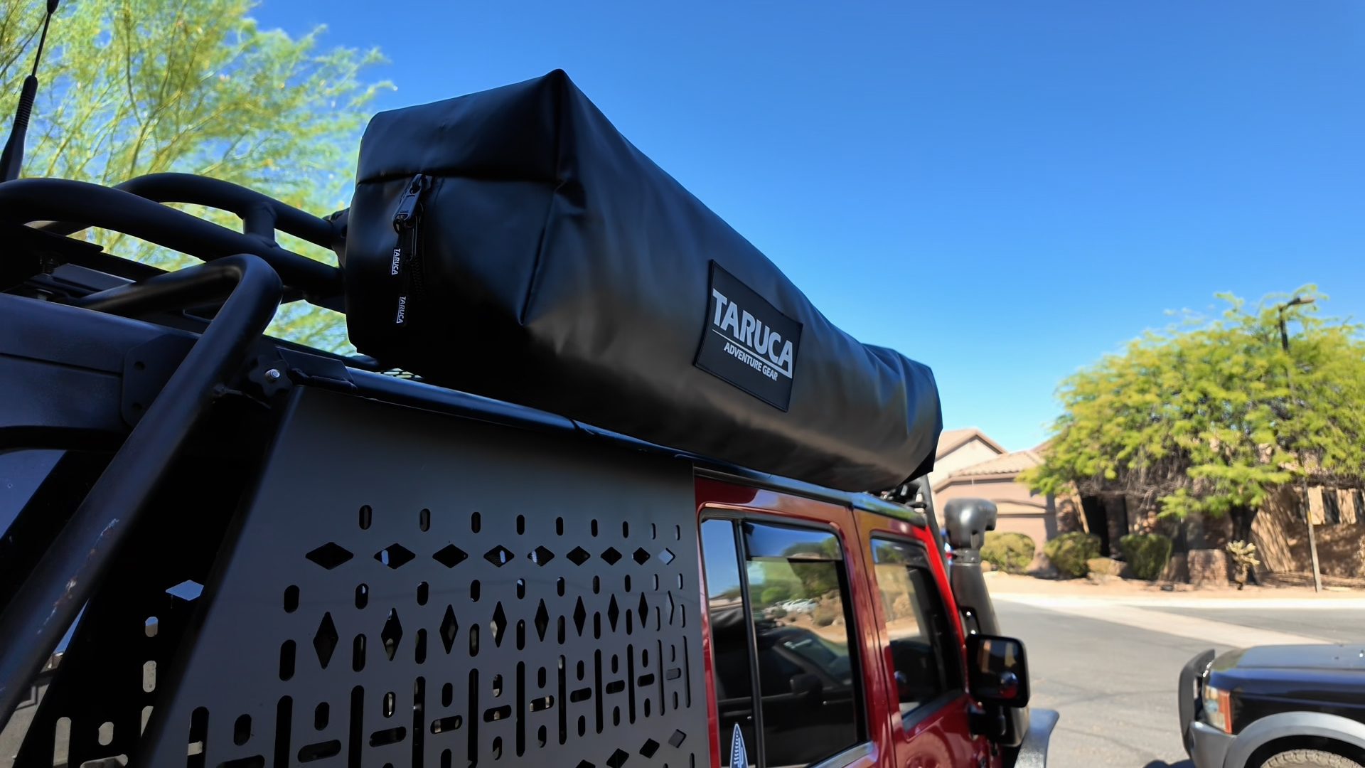 Packed Taruca ensuite mounted on the Gobi roof rack of a red Jeep