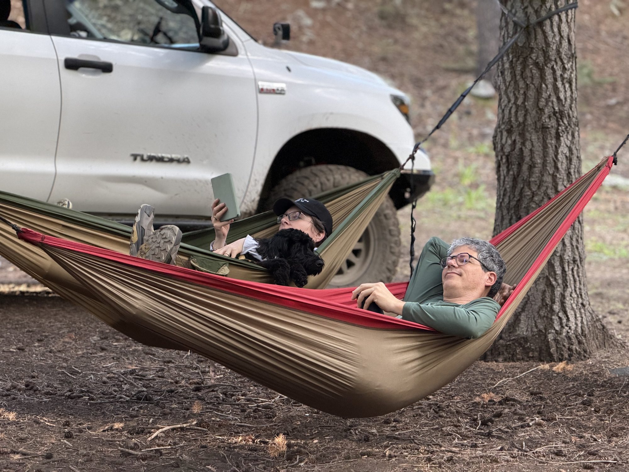 Keith and Maggie relaxing in hammocks next to their Toyota Tundra at camp