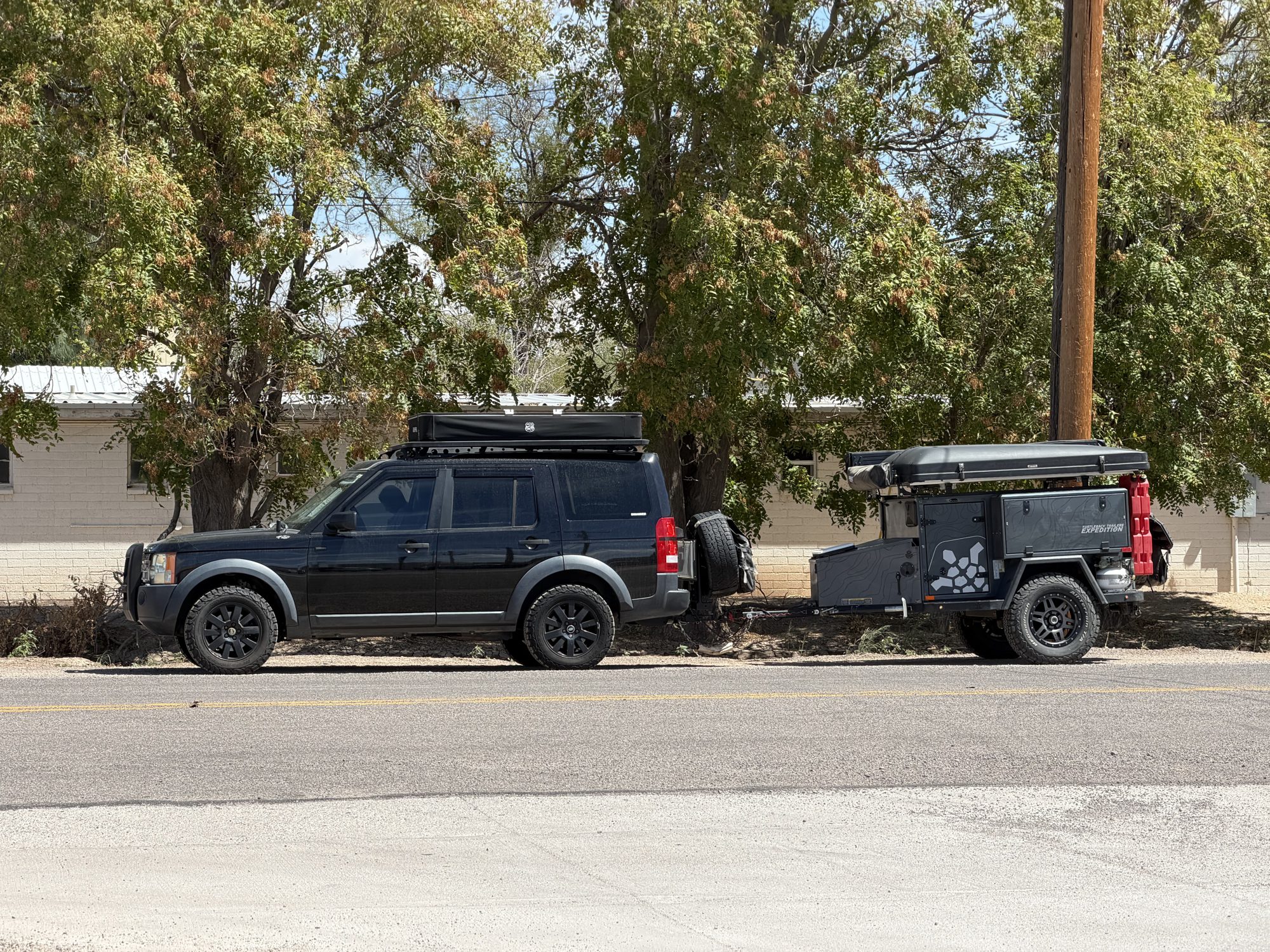 Land Rover LR3 towing a Turtleback trailer parked on a street in Pima, Arizona